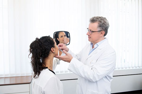 Dr. med. Domeisen kontrolliert das Ergebnis der Nasen Operation einer Patientin